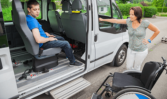 Caregiver helping passenger into accessible van