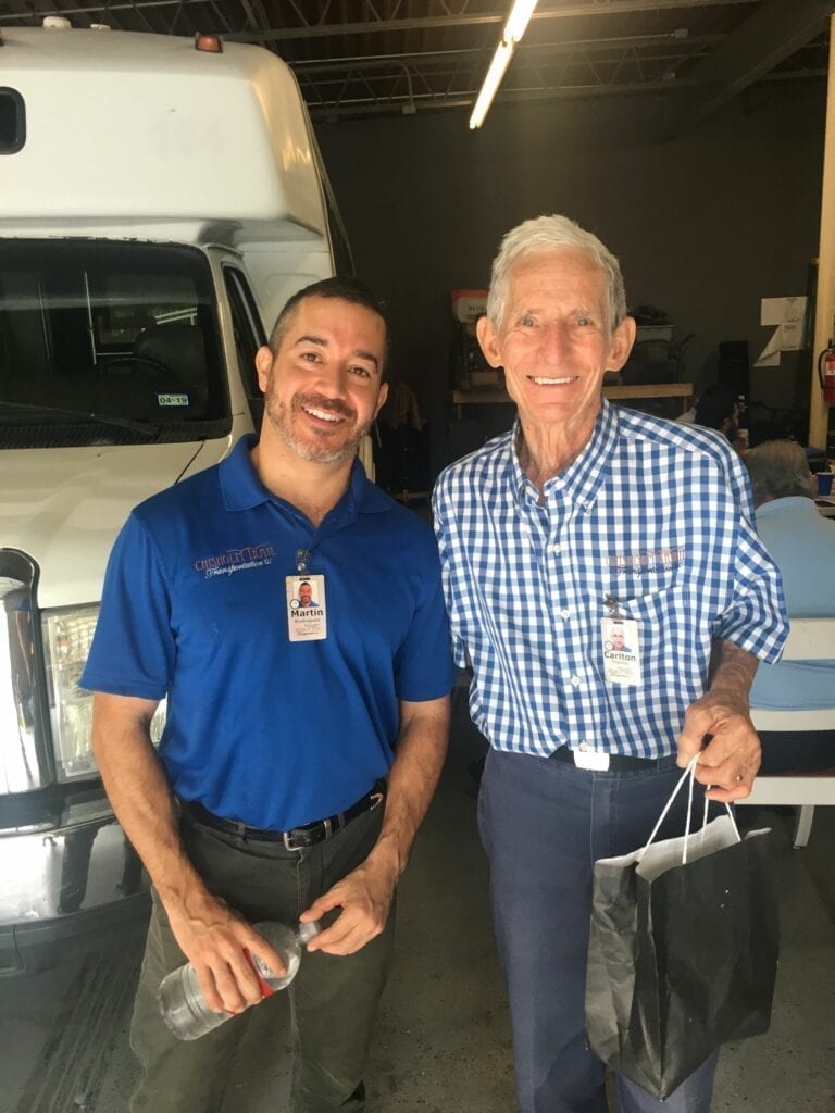 Two smiling transportation staff by vehicle