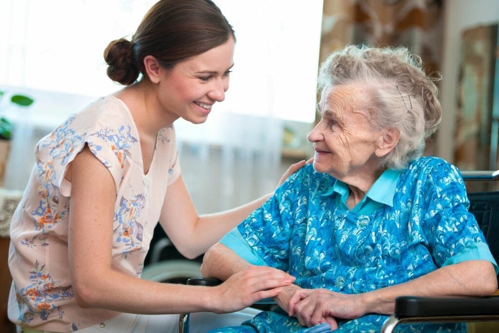 Caregiver smiling with elderly woman in wheelchair